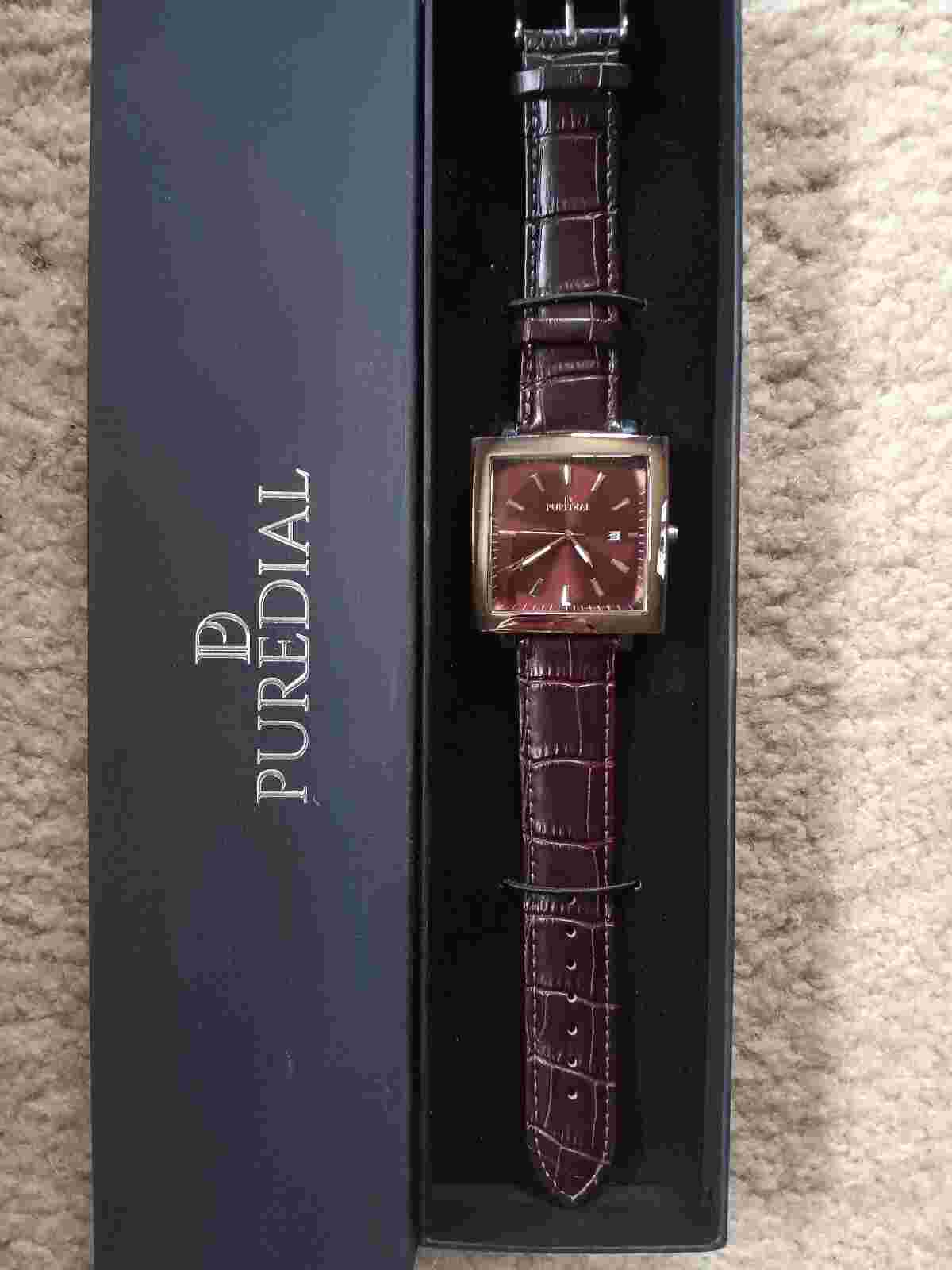 This Puredial watch has a dark brown leather band with a square stainless bezel